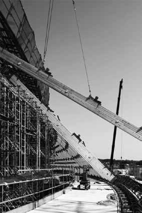 「静岡県草薙総合運動場体育館」 鉄骨トラス構造の屋根を支えるスギ集成材を取り付けている様子。